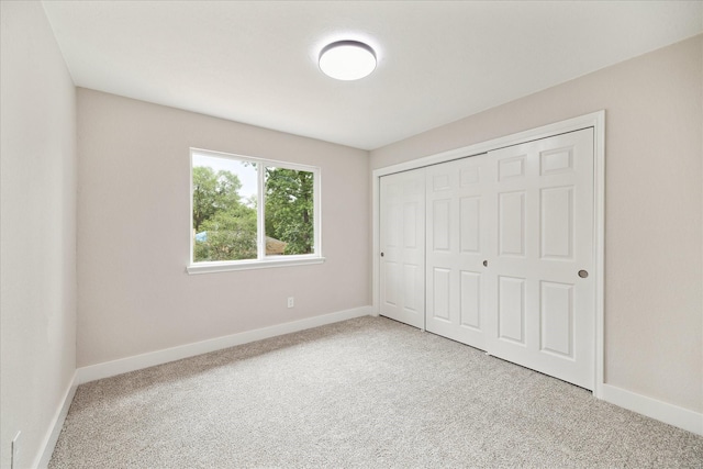 unfurnished bedroom featuring baseboards, carpet, and a closet