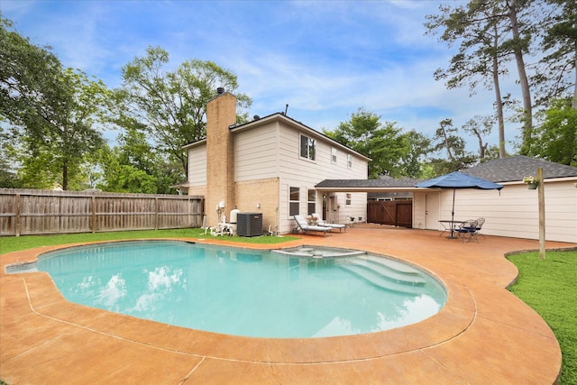 view of pool featuring a patio, a pool with connected hot tub, fence, and central AC unit