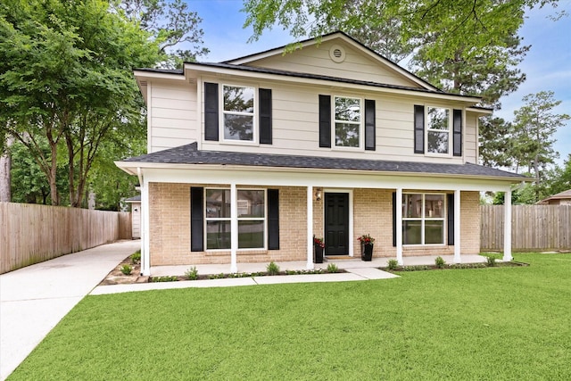 view of front of property with a porch, brick siding, fence, and a front yard