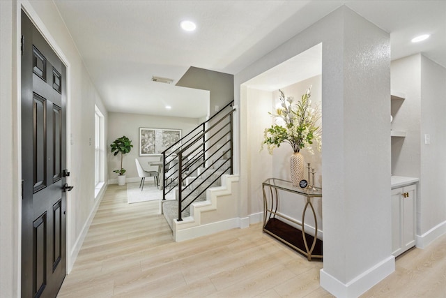 entrance foyer with baseboards, visible vents, light wood finished floors, and stairs