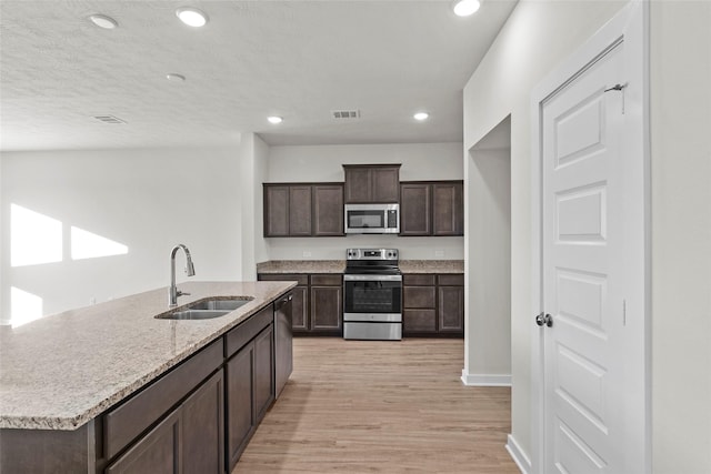 520 Shoreview Dr, Conroe, TX 77303 - kitchen with a sink, light wood-style floors, stainless steel appliances, dark brown cabinets, and visible vents