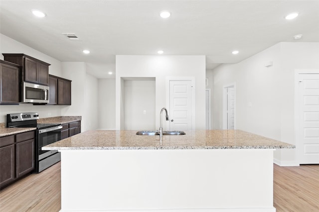 520 Shoreview Dr, Conroe, TX 77303 - kitchen with dark brown cabinetry, light stone countertops, appliances with stainless steel finishes, a sink, and visible vents