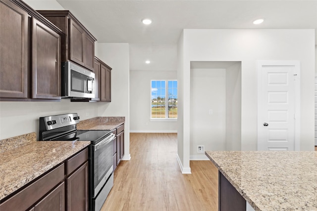 520 Shoreview Dr, Conroe, TX 77303 - kitchen with light stone countertops, stainless steel appliances, light wood-type flooring, dark brown cabinetry, and baseboards