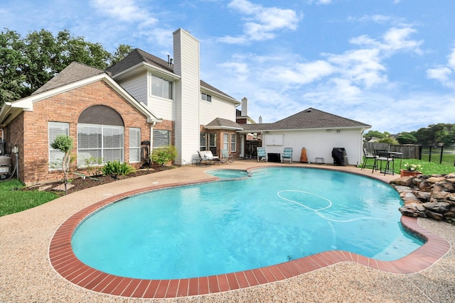 view of pool featuring a patio area, fence, and a pool with connected hot tub