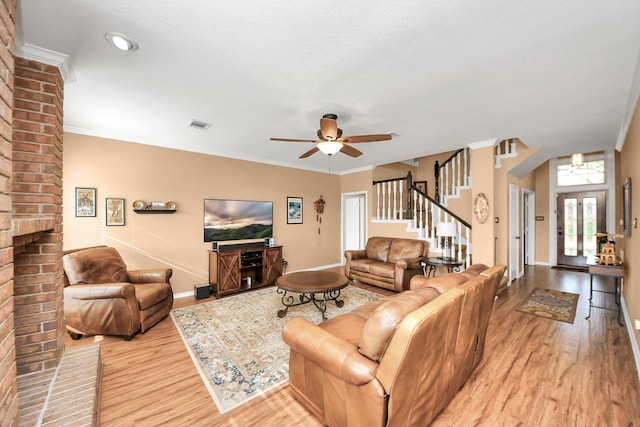 living room featuring stairs, ceiling fan, visible vents, and light wood finished floors