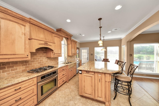 kitchen with appliances with stainless steel finishes, a sink, a kitchen breakfast bar, a kitchen island, and visible vents
