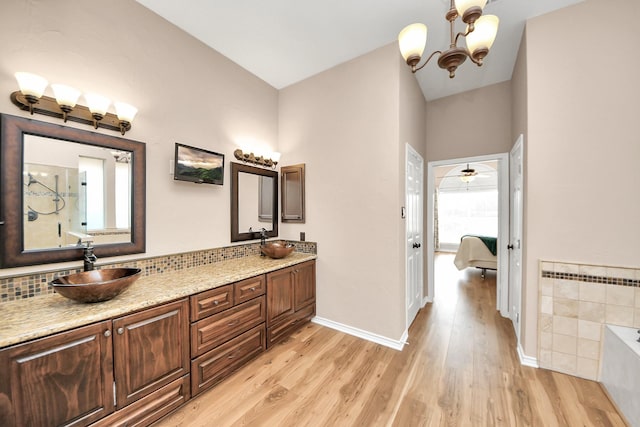full bathroom featuring a washtub, baseboards, a sink, and wood finished floors