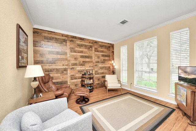 living area with crown molding, wood finished floors, and visible vents