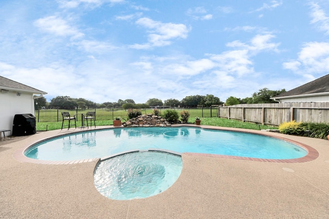 view of pool featuring a lawn, a pool with connected hot tub, and a fenced backyard
