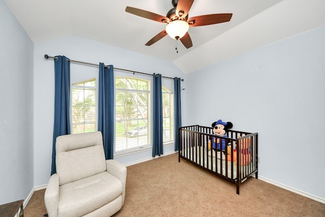 bedroom with carpet flooring, a crib, a ceiling fan, baseboards, and vaulted ceiling