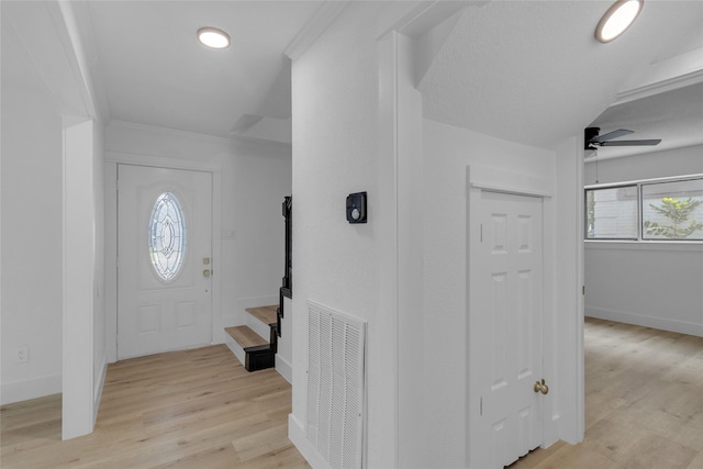 entrance foyer with visible vents, light wood-style flooring, ceiling fan, and stairway