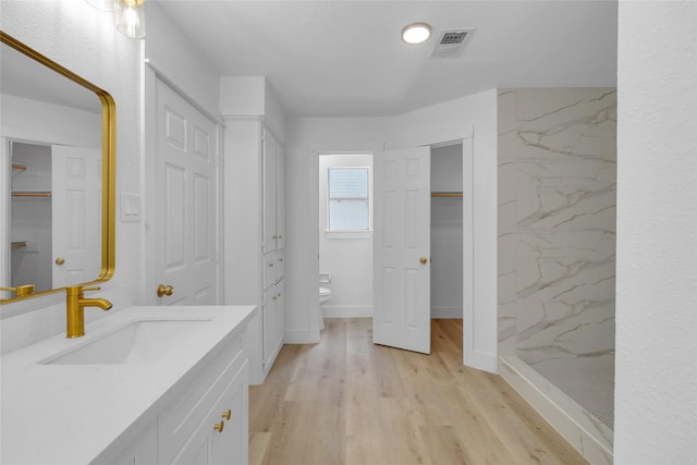 bathroom with visible vents, wood finished floors, toilet, and a walk in shower