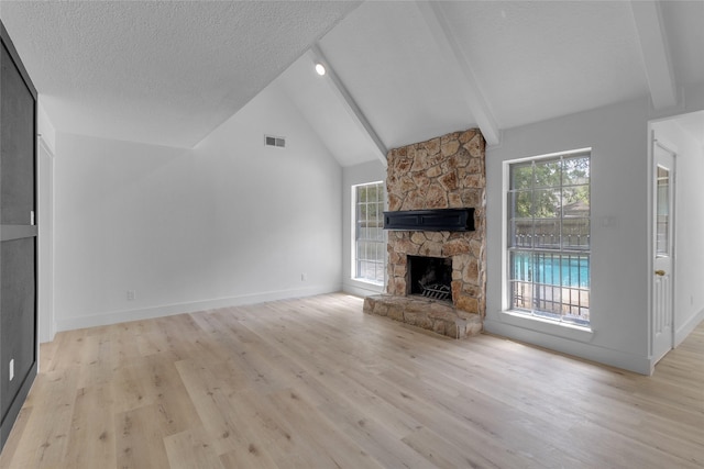 unfurnished living room with light wood finished floors, a fireplace, lofted ceiling with beams, visible vents, and a textured ceiling