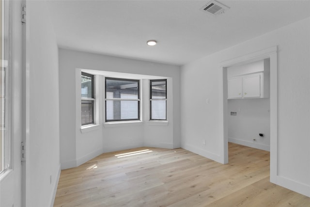 empty room featuring visible vents, baseboards, and light wood-style floors