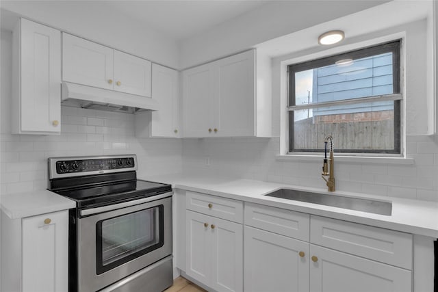kitchen with white cabinets, a sink, light countertops, under cabinet range hood, and stainless steel electric range