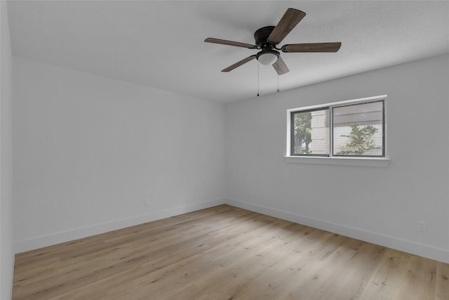 spare room featuring baseboards, light wood-type flooring, and ceiling fan
