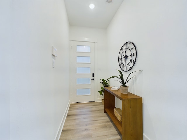 doorway to outside with baseboards, visible vents, and light wood finished floors