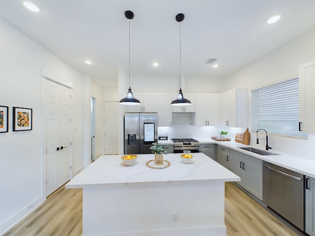 kitchen featuring gray cabinetry, light wood-style floors, stainless steel appliances, and a sink