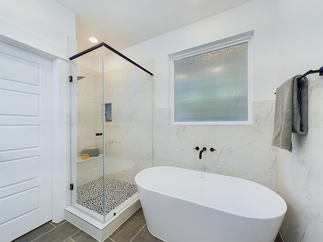 bathroom with tile walls, wainscoting, a freestanding bath, and a shower stall