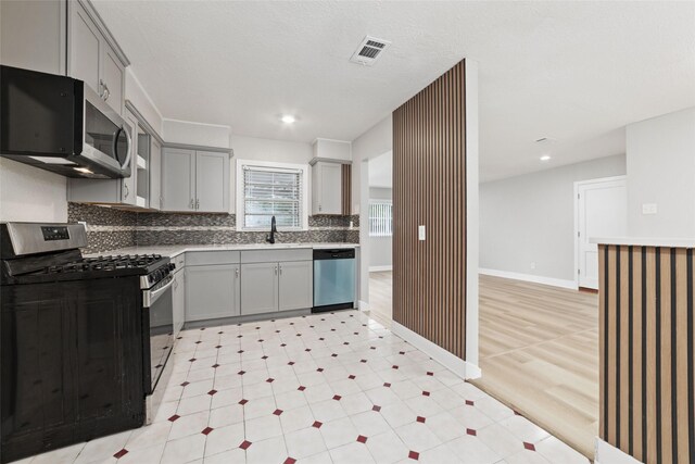 4517 W 43rd St, Houston, TX 77092 - kitchen featuring gray cabinets, light floors, stainless steel appliances, backsplash, and visible vents