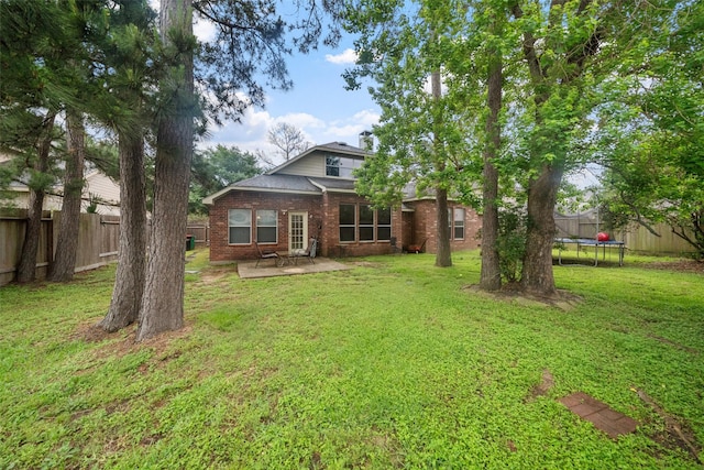 15015 Cozy Hollow Ln, Houston, TX 77044 - back of house featuring a trampoline, brick siding, a patio area, and a chimney