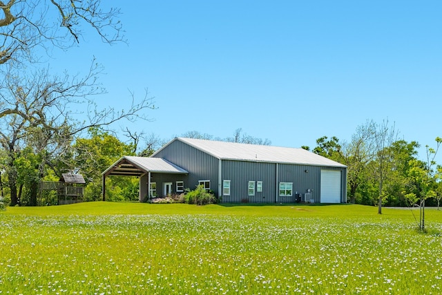 back of house with an outdoor structure, a pole building, metal roof, a lawn, and a garage