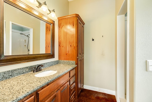 bathroom featuring walk in shower, vanity, and baseboards