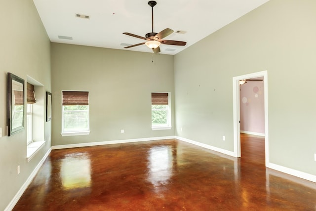 spare room featuring concrete flooring, a wealth of natural light, ceiling fan, and high vaulted ceiling