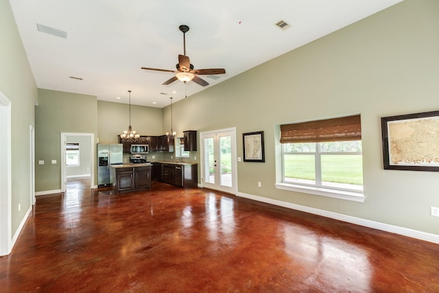 unfurnished living room featuring visible vents, concrete floors, ceiling fan with notable chandelier, baseboards, and high vaulted ceiling