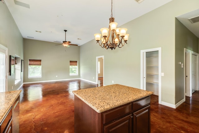kitchen with a high ceiling, ceiling fan with notable chandelier, finished concrete flooring, and baseboards