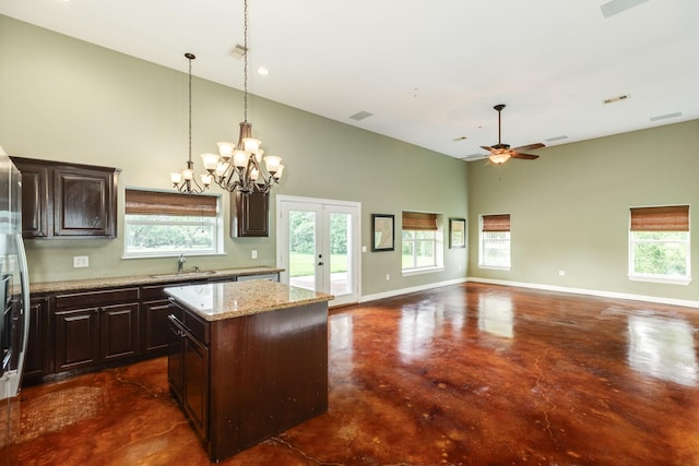 kitchen featuring a high ceiling, concrete flooring, a center island, dark brown cabinetry, and french doors