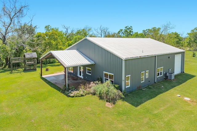 back of house with metal roof, a detached garage, a yard, and an outbuilding