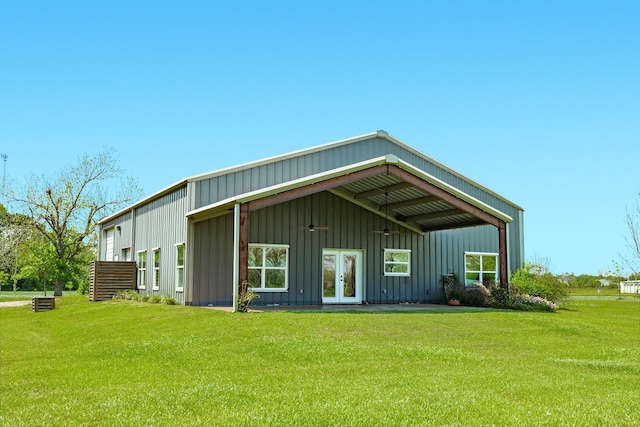 rear view of house with board and batten siding, a yard, and french doors