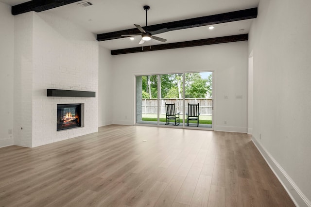 1222 Tallow Park Ln, Pinehurst, TX 77362 - unfurnished living room featuring beam ceiling, wood finished floors, a ceiling fan, a brick fireplace, and baseboards