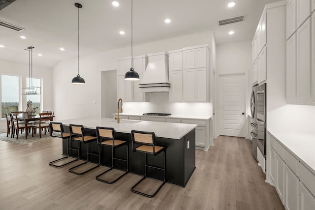 1222 Tallow Park Ln, Pinehurst, TX 77362 - kitchen with custom range hood, light wood-style flooring, a sink, a breakfast bar area, and recessed lighting