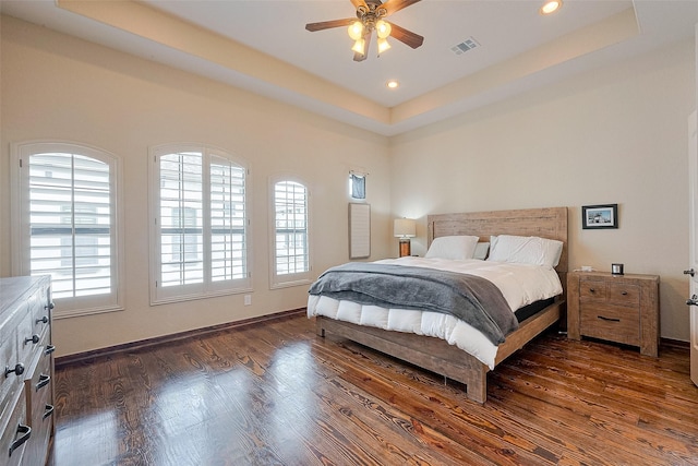 bedroom featuring dark wood-type flooring, visible vents, a raised ceiling, and recessed lighting