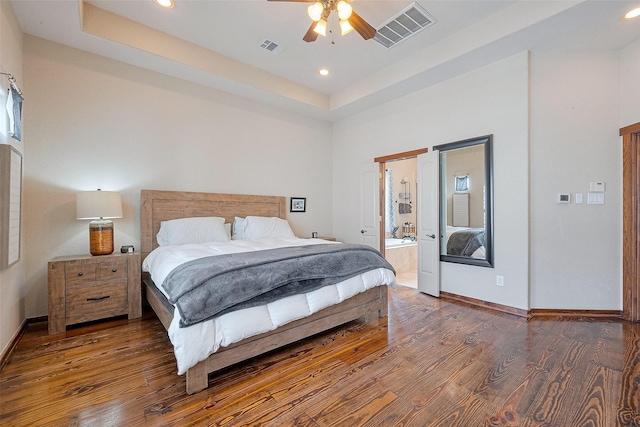 bedroom with visible vents, wood finished floors, and a tray ceiling