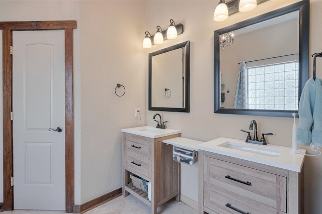 full bath with two vanities, baseboards, and a sink