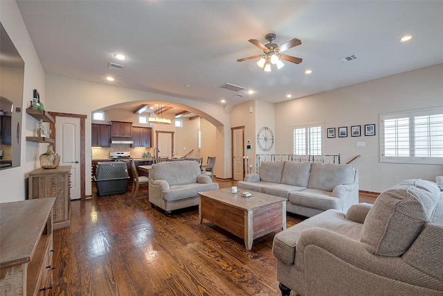 living area with visible vents, a ceiling fan, dark wood finished floors, and arched walkways