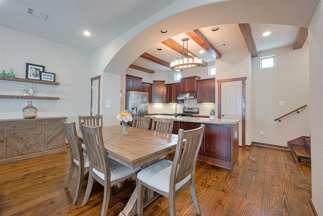 dining space with dark wood finished floors, visible vents, and beamed ceiling
