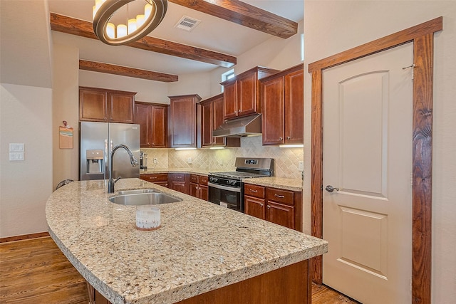 kitchen with decorative backsplash, a sink, stainless steel appliances, under cabinet range hood, and beam ceiling