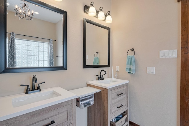 bathroom with two vanities, a notable chandelier, and a sink