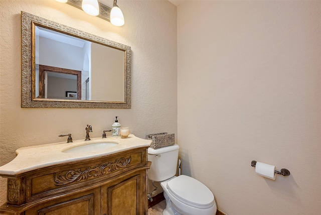 bathroom featuring vanity, toilet, and a textured wall