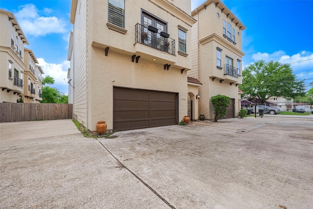 exterior space with concrete driveway, a garage, stucco siding, and fence