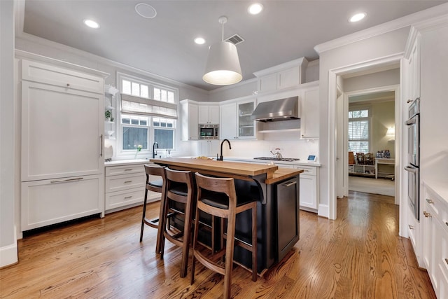 4020 Sul Ross St, Houston, TX 77027 - kitchen with wall chimney exhaust hood, wooden counters, white cabinets, and stainless steel appliances