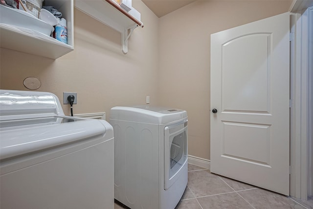 clothes washing area with light tile patterned flooring, washer and dryer, and laundry area