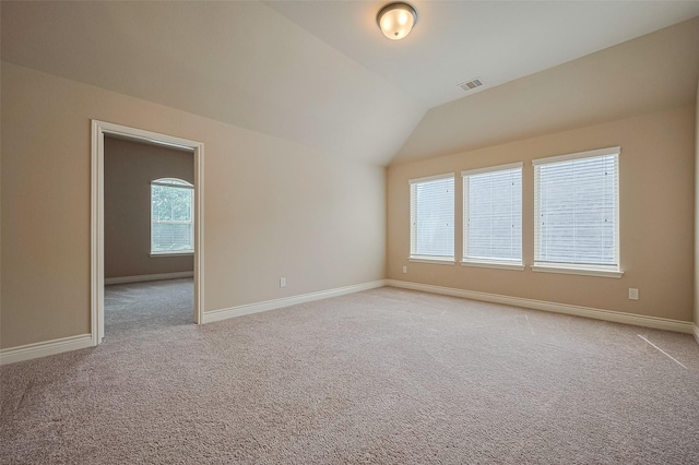 spare room featuring visible vents, vaulted ceiling, light colored carpet, and baseboards