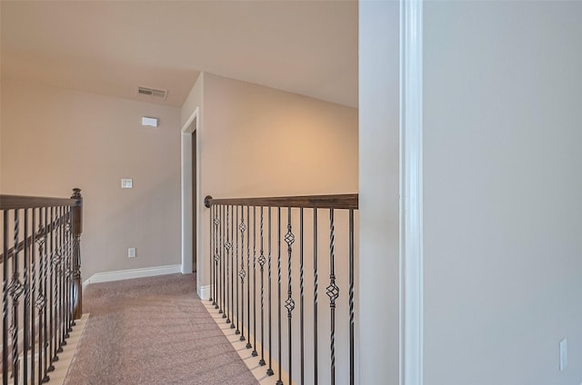 hall featuring visible vents, light carpet, and baseboards