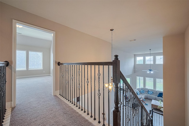 corridor featuring an upstairs landing, carpet flooring, baseboards, and visible vents
