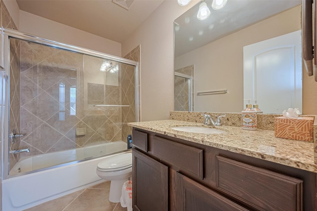 bathroom with tile patterned floors, toilet, vanity, visible vents, and bath / shower combo with glass door